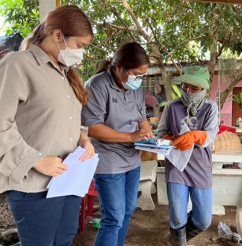 Three people wearing masks. One is holding white a4 paper. Another is taking papers from the third person
