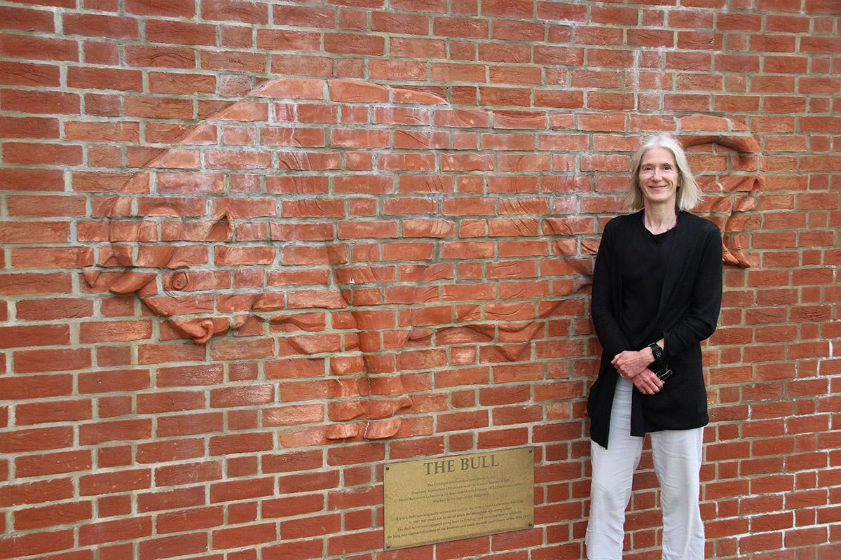 Sue stood by by red brick wall